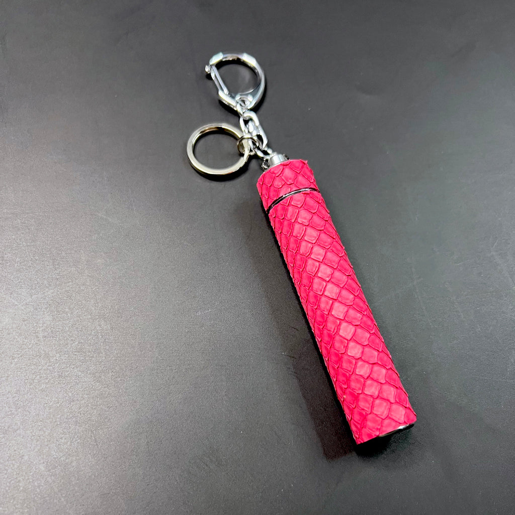 Barbie pink python leather key charm and J holder styled on dark background