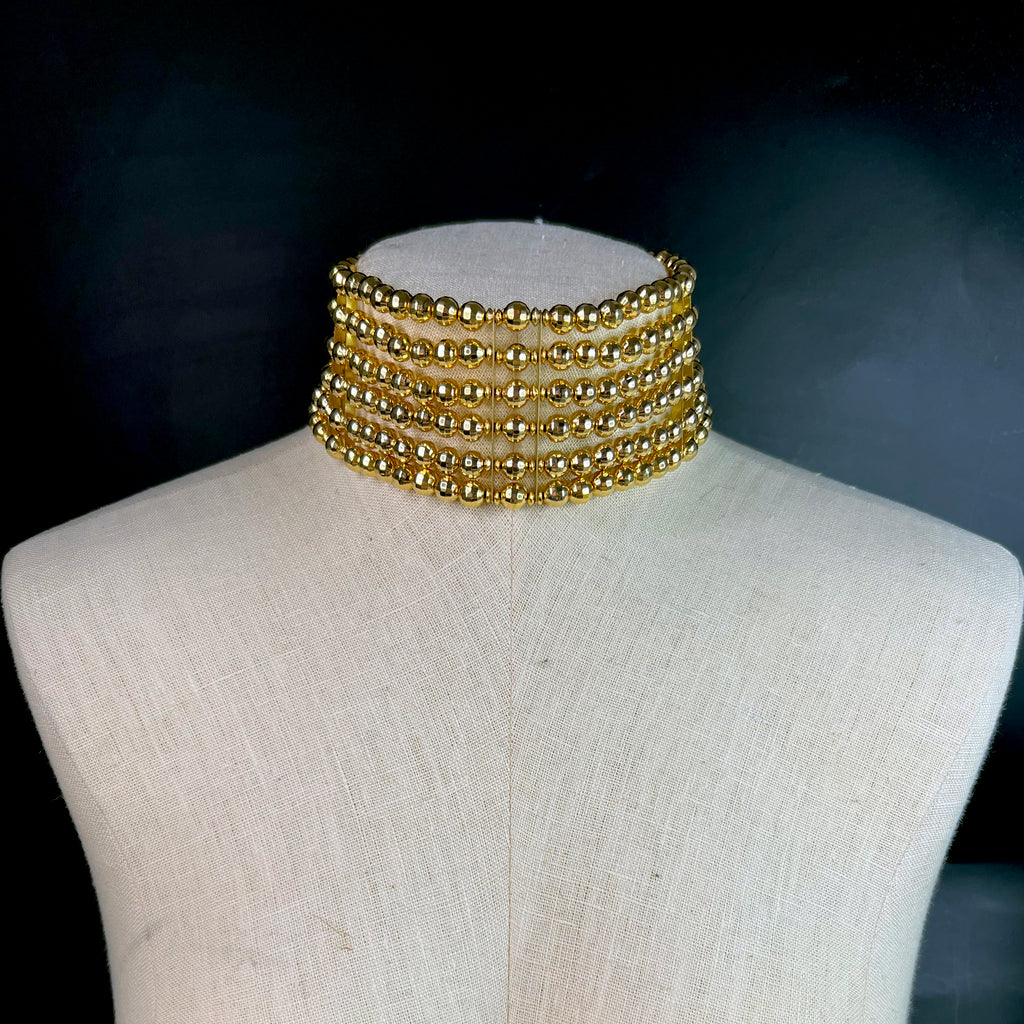 Wide gold beaded choker necklace displayed on a mannequin – layered collar-style fashion jewelry