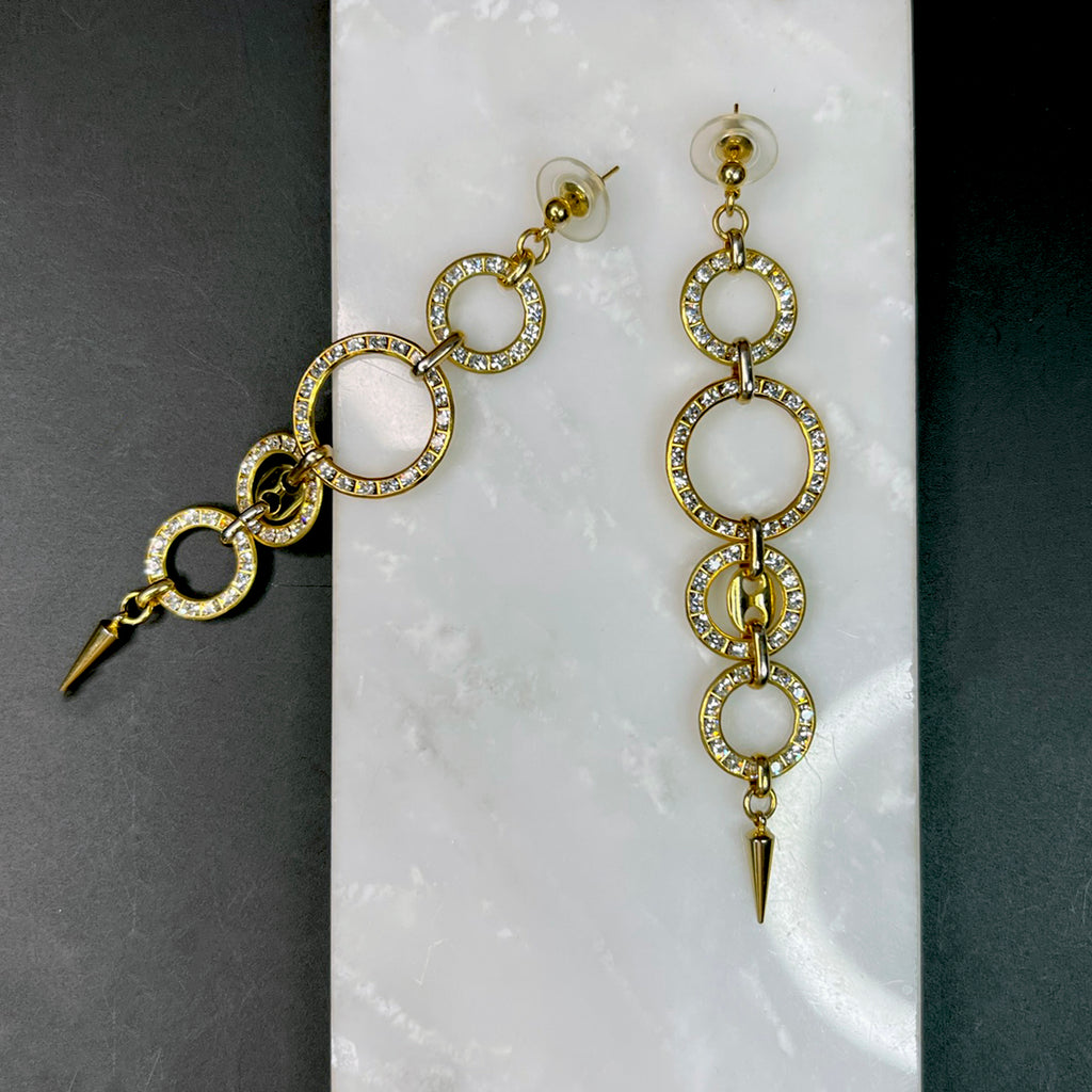 Artistic flat lay of rhinestone hoop dangle earrings on contrasting white and black surfaces, one earring angled for a dimensional view.