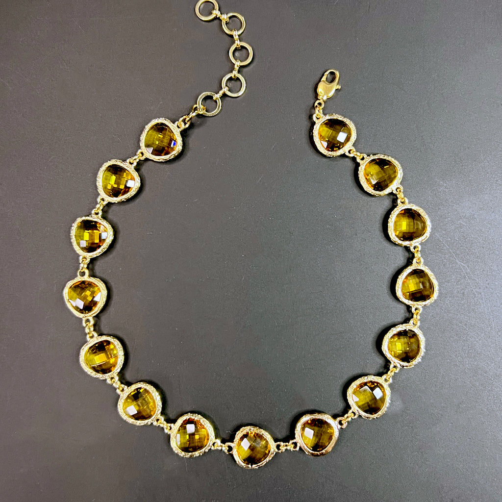 Yellow gemstone choker necklace with warm citrine-hued crystals in rich gold-toned bezels, styled in a curve over a matte black surface.
