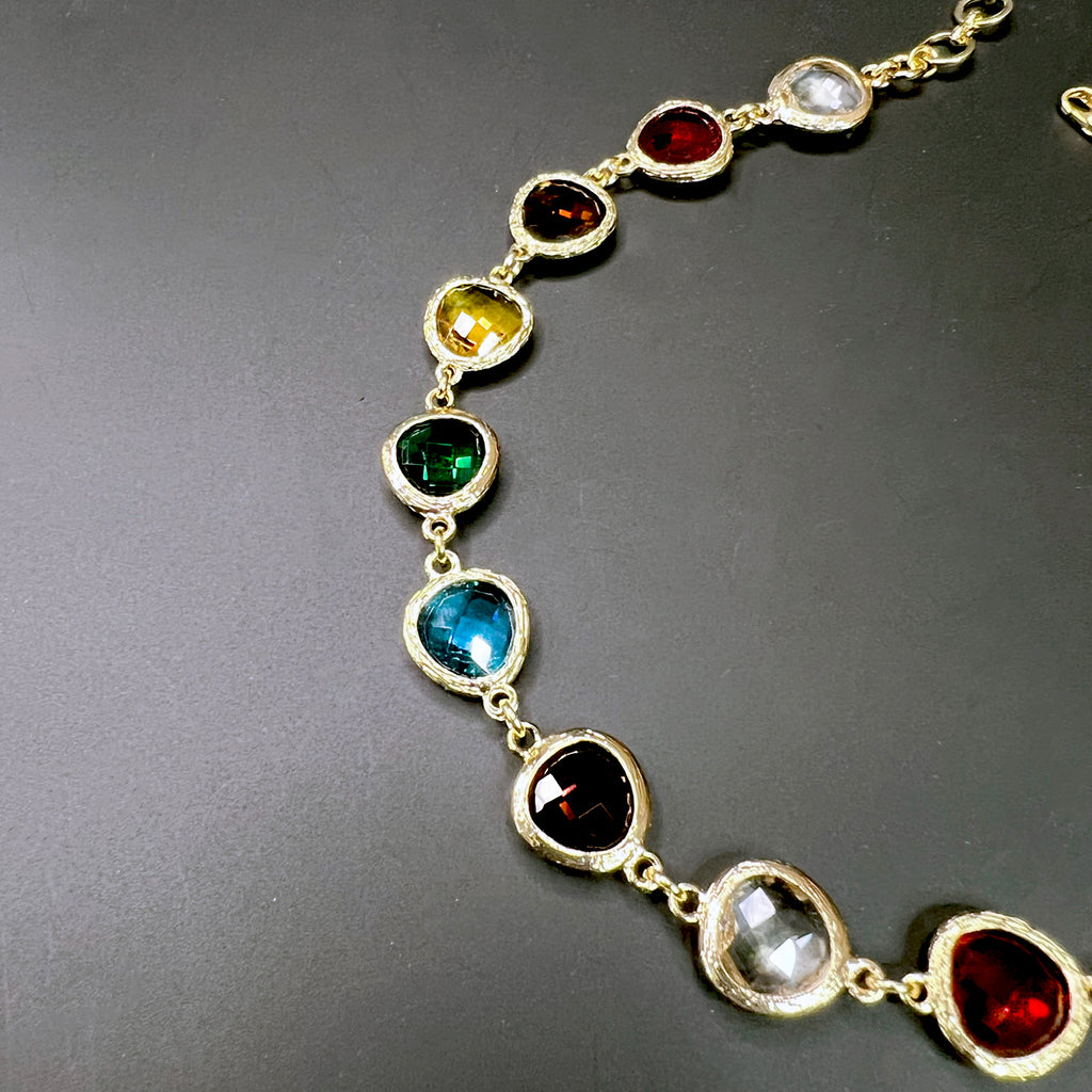 Detailed view of jewel-toned stones including blue, green, and red crystals set in gold links