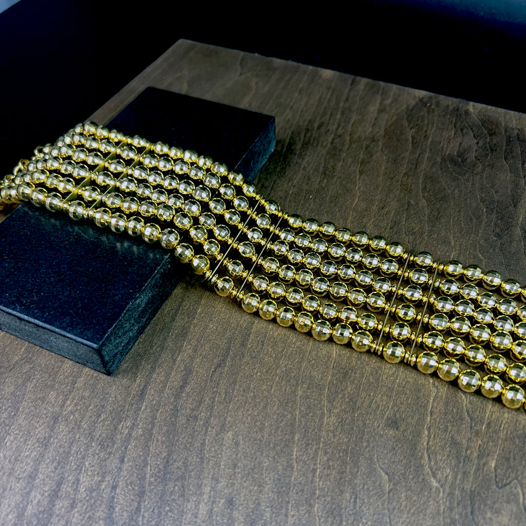 Close-up of faceted gold beads in layered strands – detailed view of choker necklace design