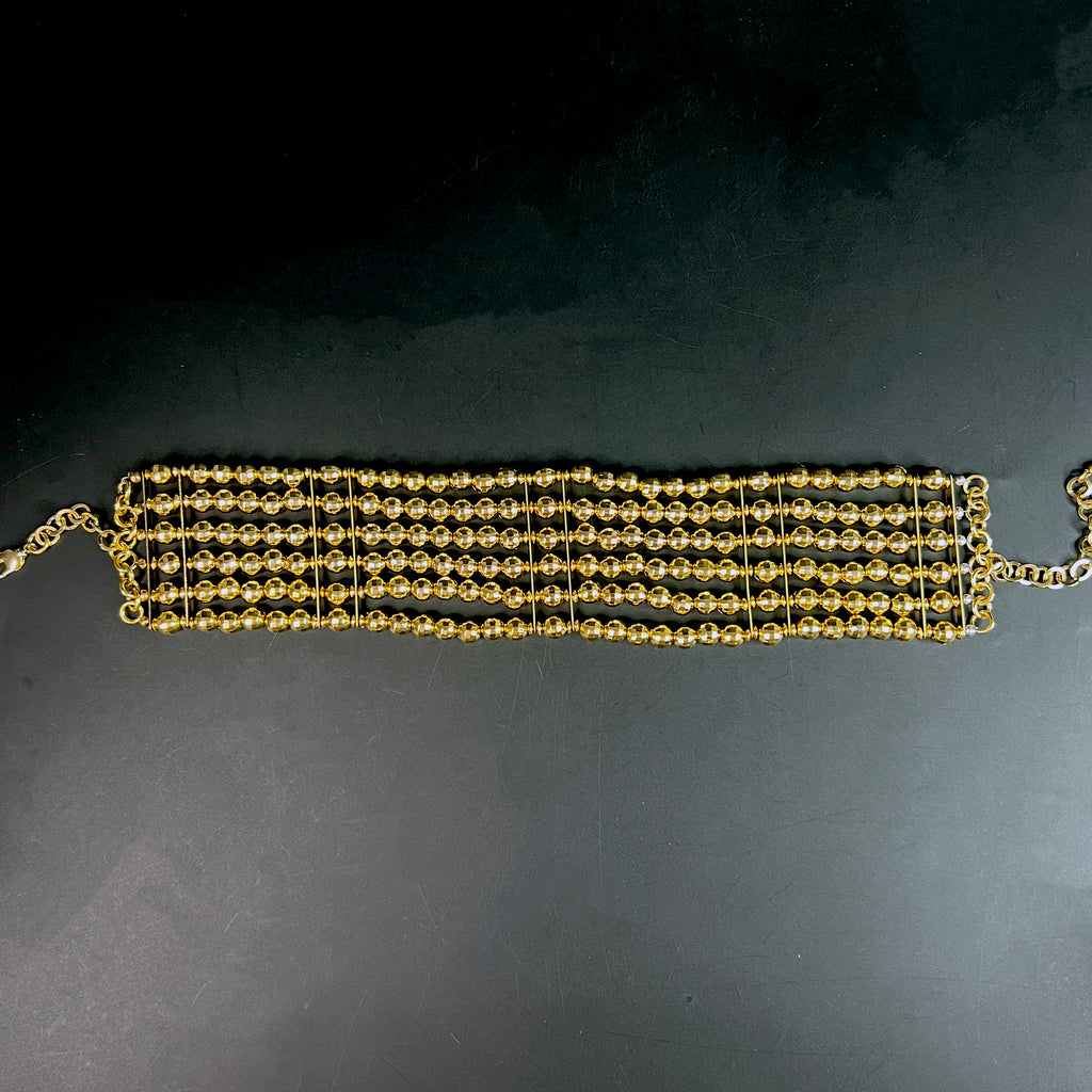 Top-down image of wide gold collar necklace with multiple bead rows – fashion-forward jewelry styling