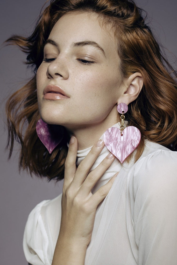Model wearing oversized pink Romantic Heart Statement Earrings with white turtleneck for a chic fashion-forward look