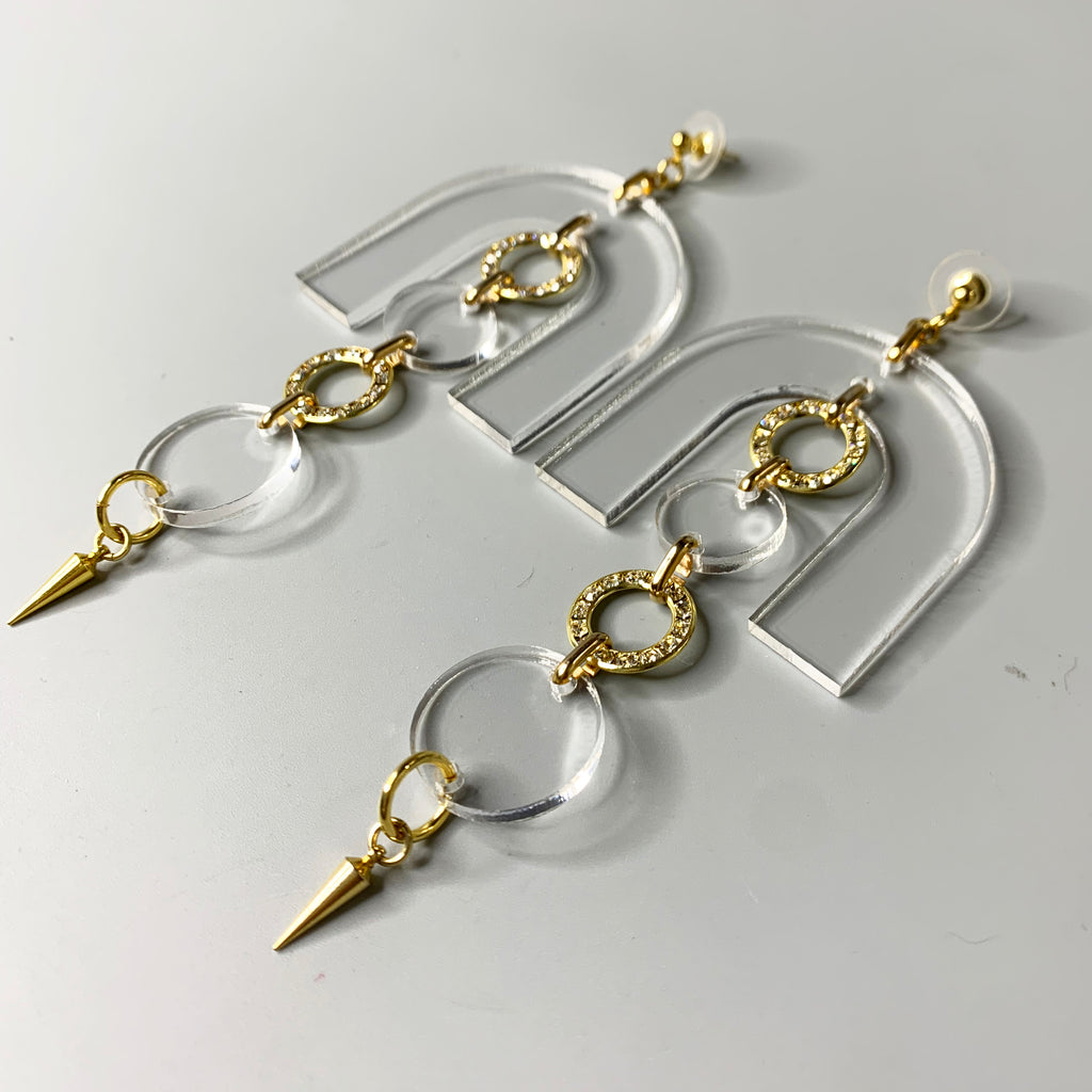 Clear acrylic and gold drop earrings with arch design, crystal rings, and spike charm