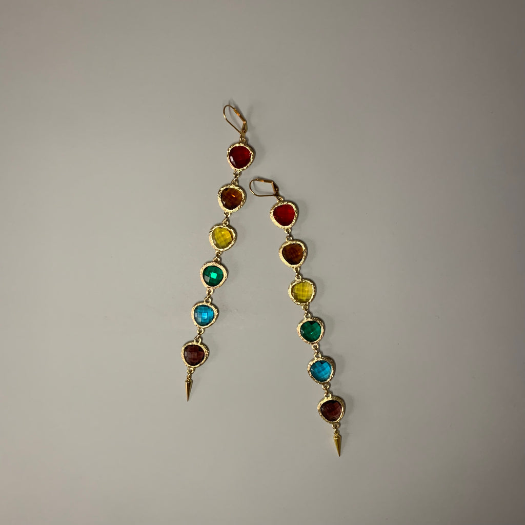 Angled view of linear rainbow crystal earrings with gold hardware and pointed tips – bold colorful statement earrings