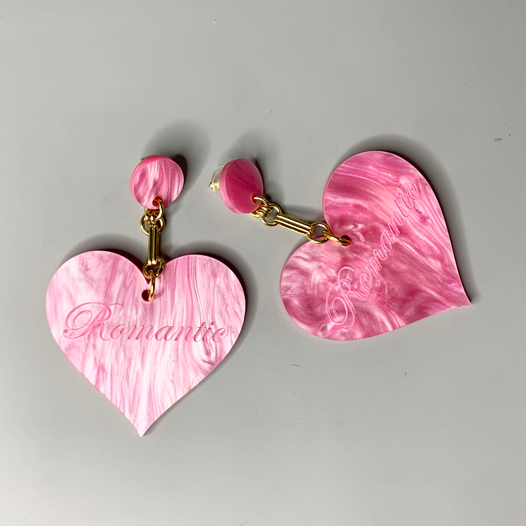Close-up of pink Romantic Heart Statement Earrings featuring bold heart shapes and gold chain links