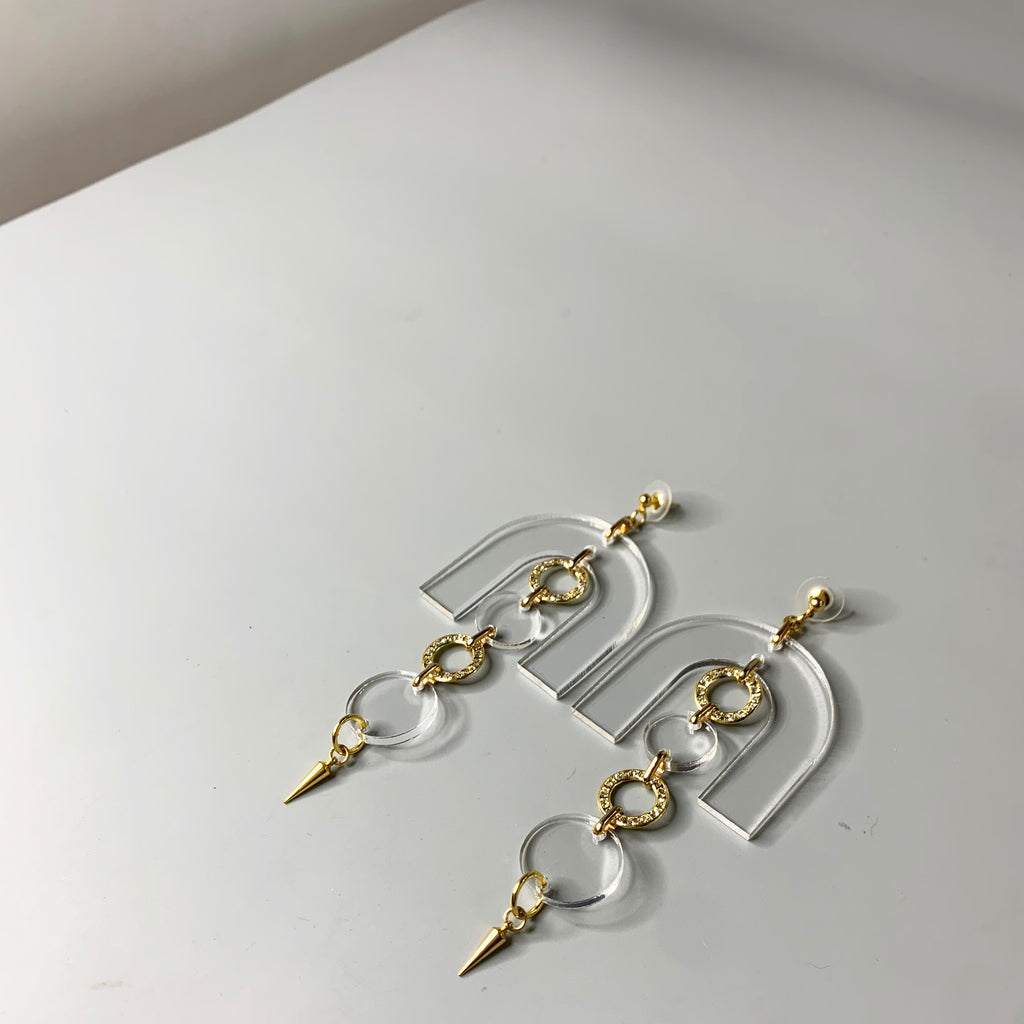 Lucite statement earrings featuring gold crystal-studded circles and sculptural arch shape