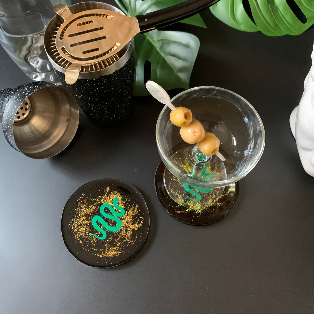 Black and gold glitter resin drink coasters with mirrored green serpent encased inside