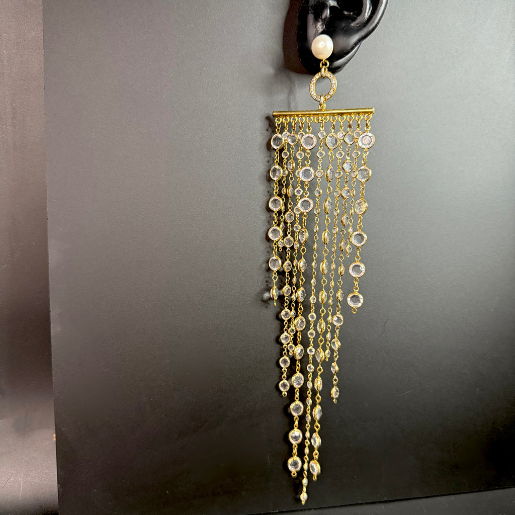 Full view of the ultra-long gold crystal fringe earring showing the pearl top, pavé ring, and multiple strands of clear crystals.