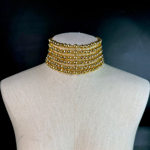 Wide gold beaded choker necklace displayed on a mannequin – layered collar-style fashion jewelry