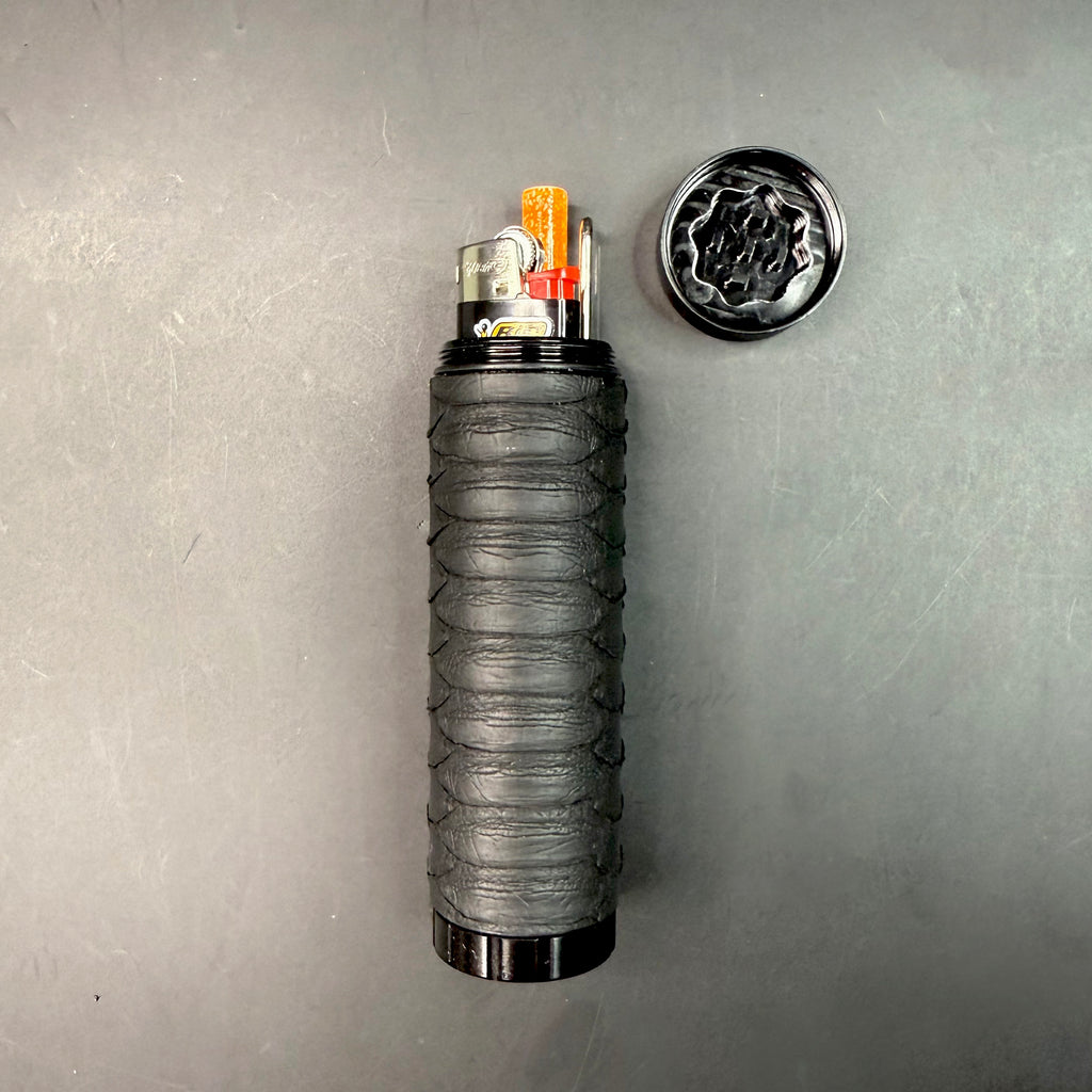 Open dugout with lighter, one-hitter, and poker tool inserted, positioned beside the removed grinder lid on a dark surface.