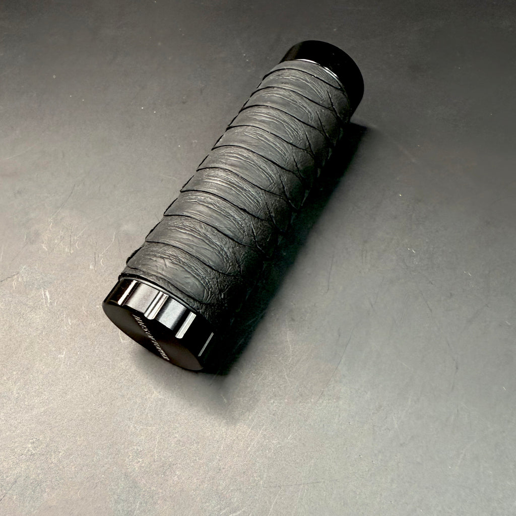 Angled close-up of the Matte Black Python Dugout lying on its side, showcasing the matte python texture and glossy black hardware base.