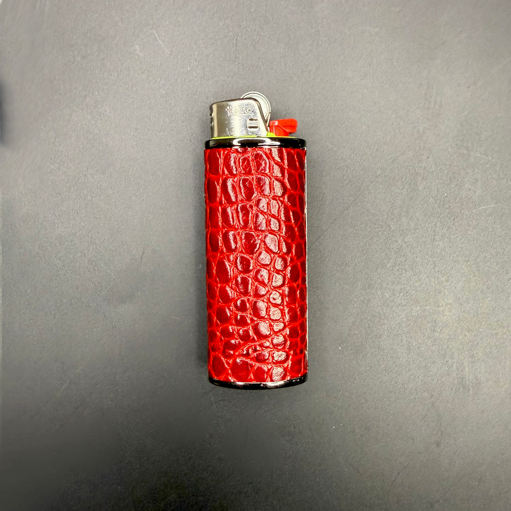 Red croc-embossed calfskin Haus of Topper Classic lighter case with glossy finish and black metal trim, shown with a Bic lighter on a charcoal background.
