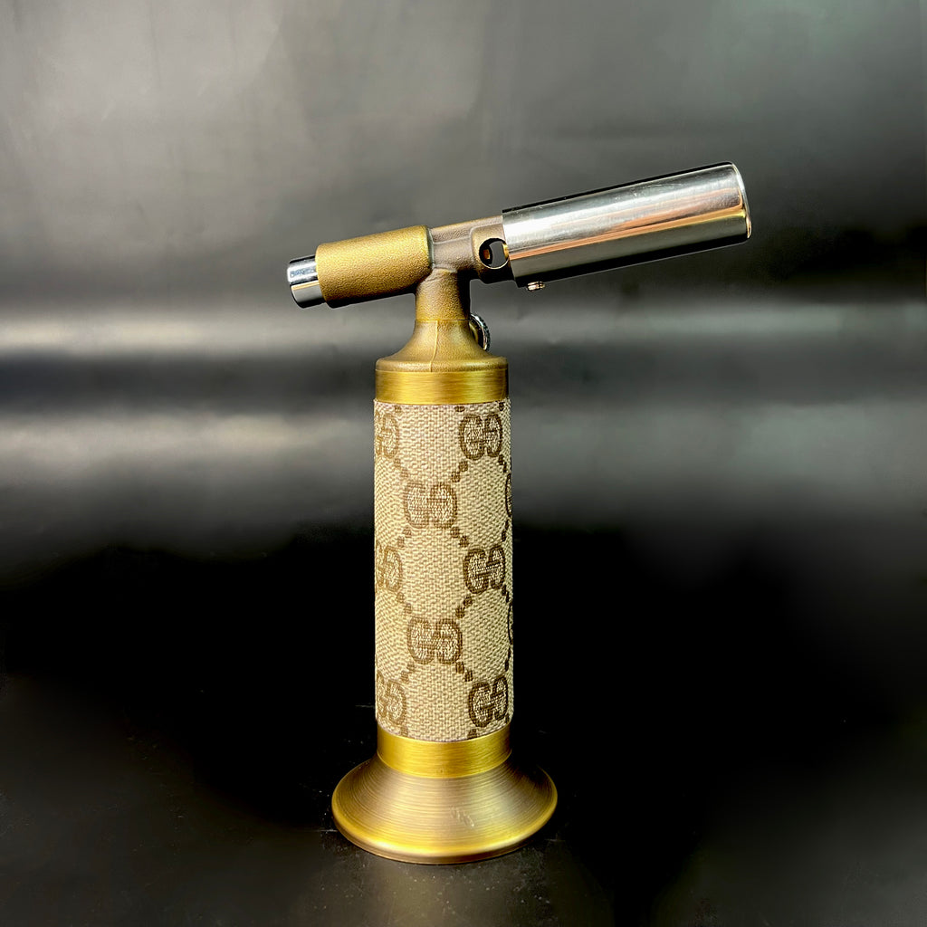 Profile view of vintage GG torch with extended chrome flame barrel and GG canvas body.