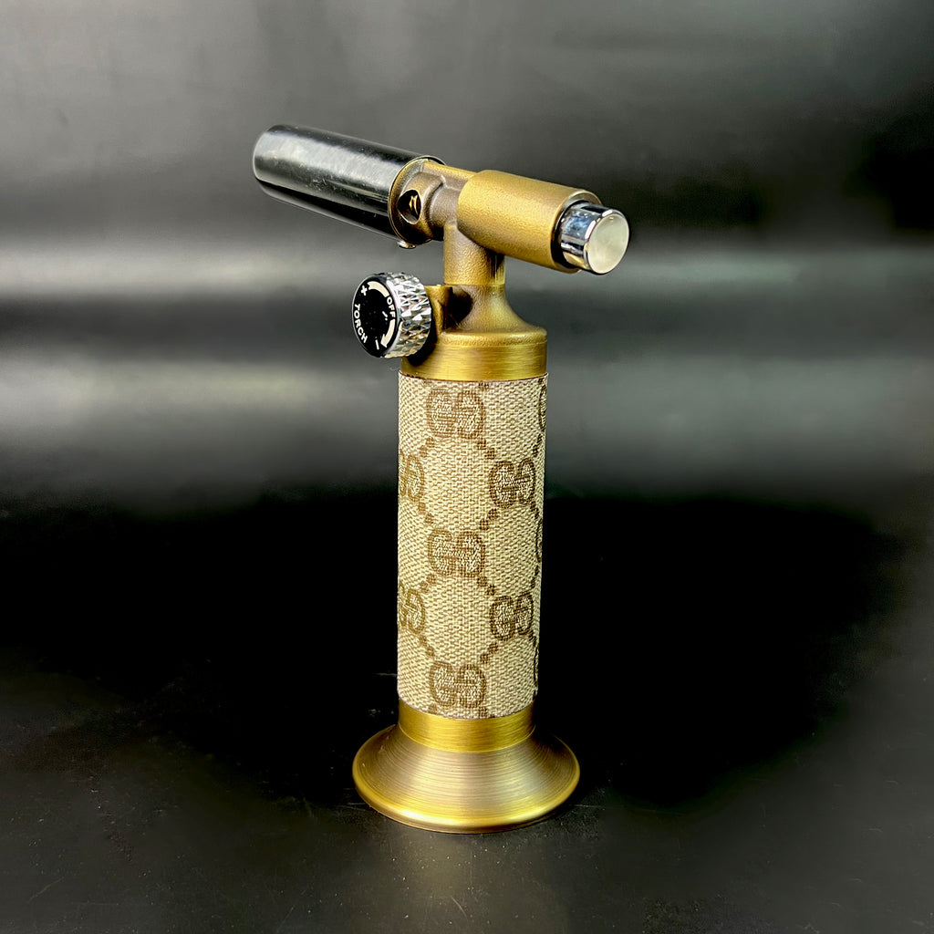 Vintage GG wrapped torch standing upright on black background with brass base and flame control knob.