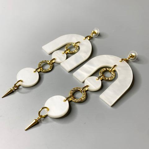 Side view of sculptural pearl acrylic earrings with gold accents and layered drop design