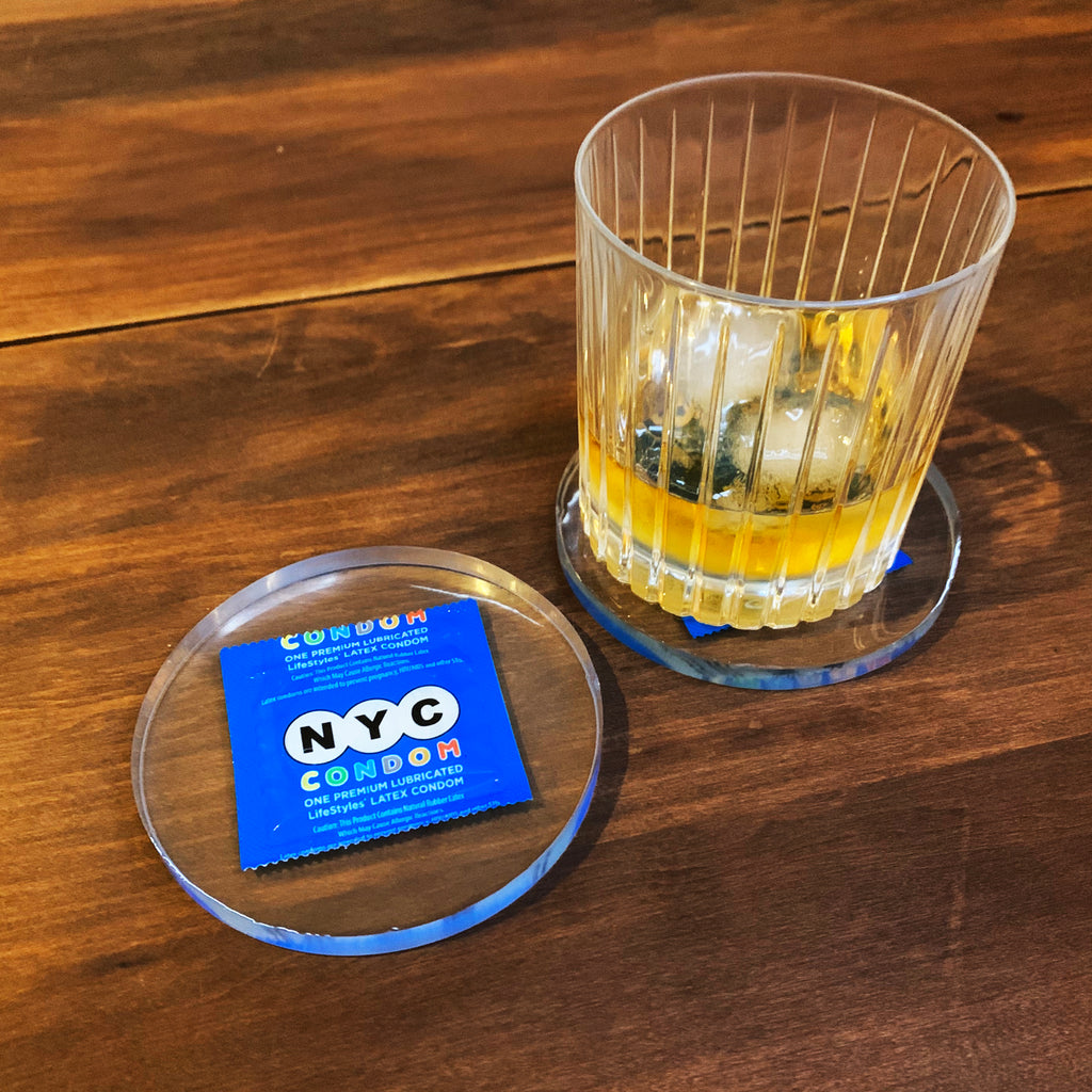 Clear resin drink coaster with blue NYC condom encased inside