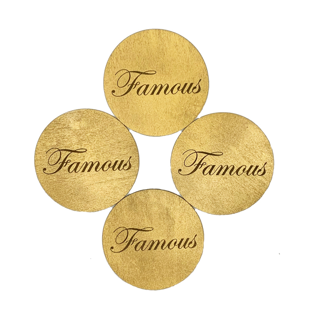 Round wood coasters coated in metallic gold enamel engraved with the word "Famous"