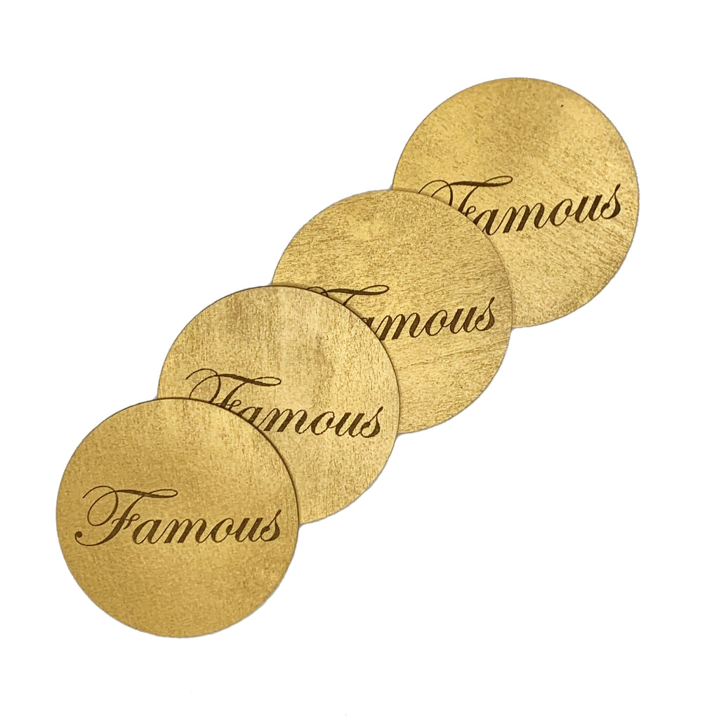 Round wood coasters coated in gold enamel engraved with the word "Famous"