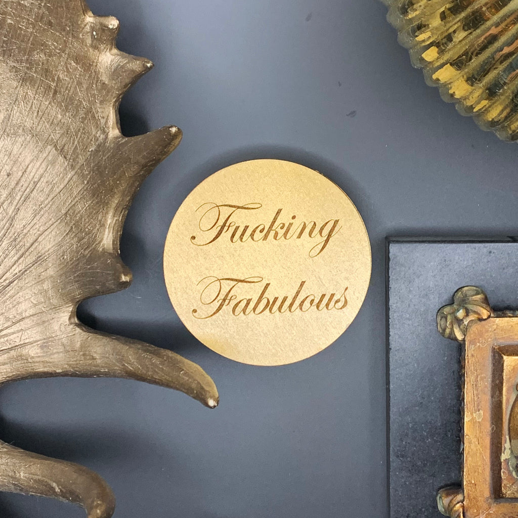 4" diameter round wood coasters coated in gold enamel and engraved with the phrase "Fucking Fabulous" in cursive