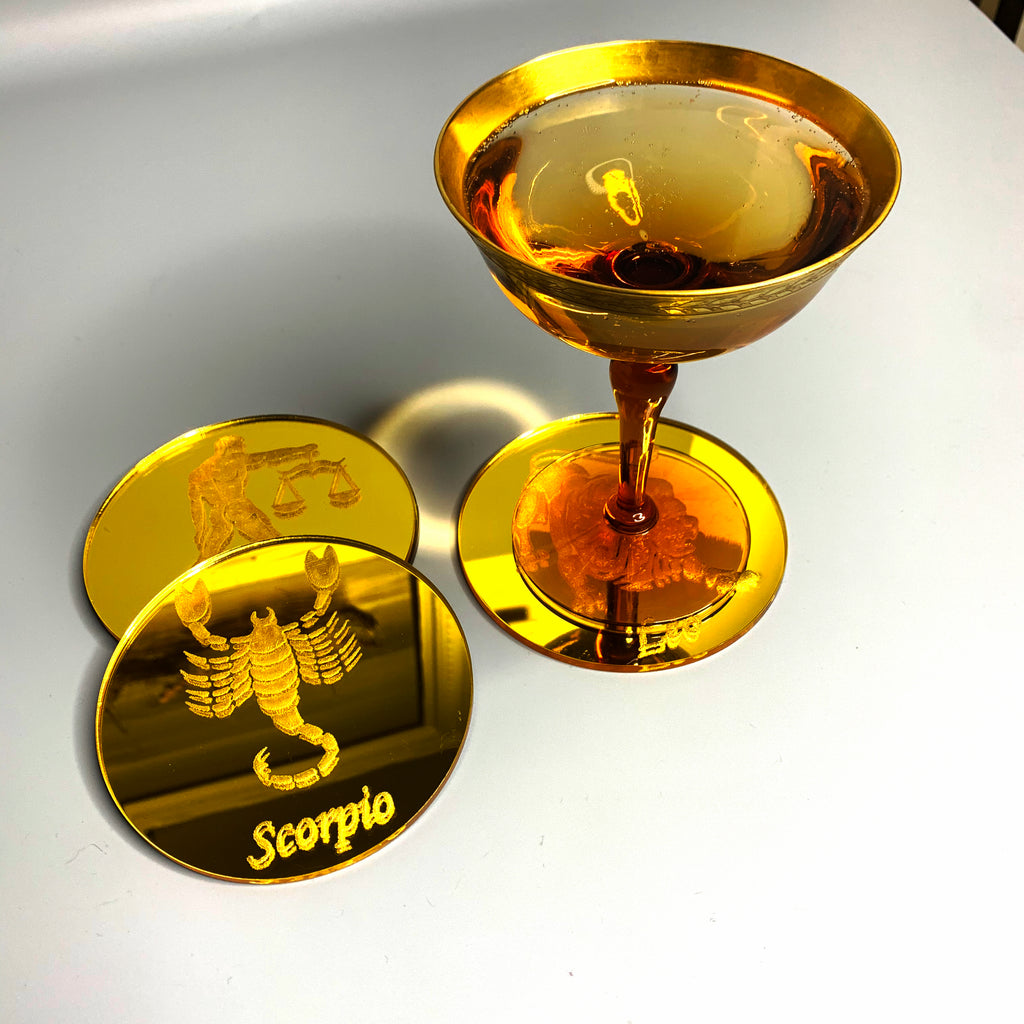 Round, gold mirrored acrylic drink coasters engraved with the scorpion zodiac sign