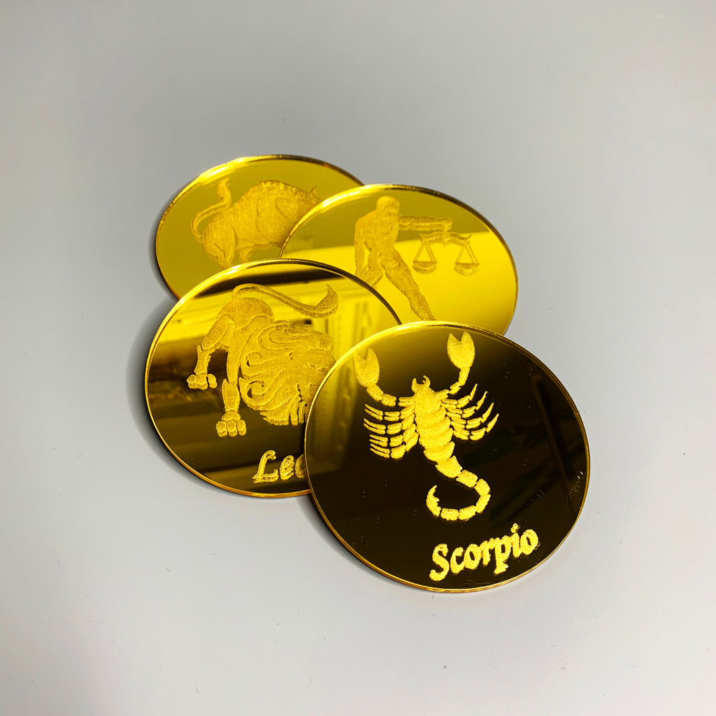 Round, gold mirrored acrylic drink coasters engraved with the zodiac signs