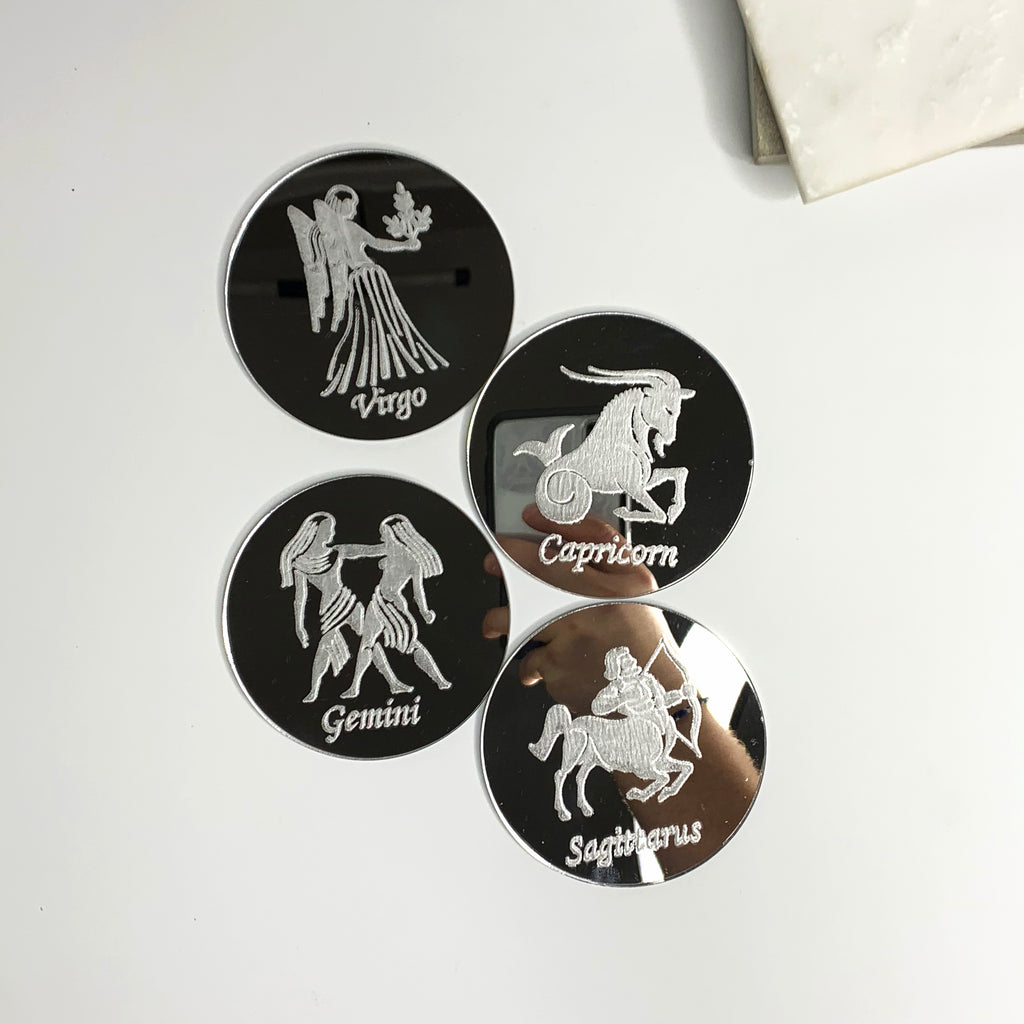 Round mirrored acrylic astrology coasters each engraved with a different zodiac sign